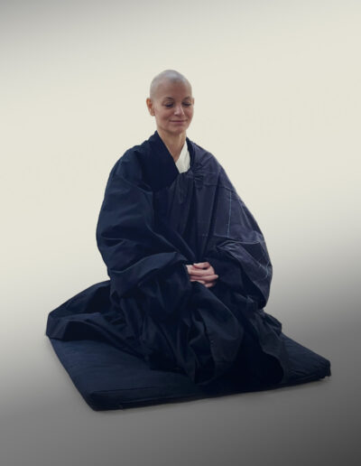 A Sesnsei kneeling on a pillow while meditating.