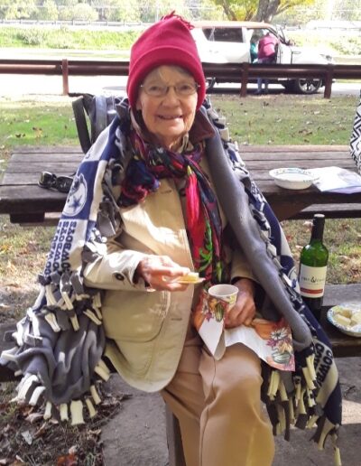 Barbara Craig sitting at a picnic table wearing a pink hat.
