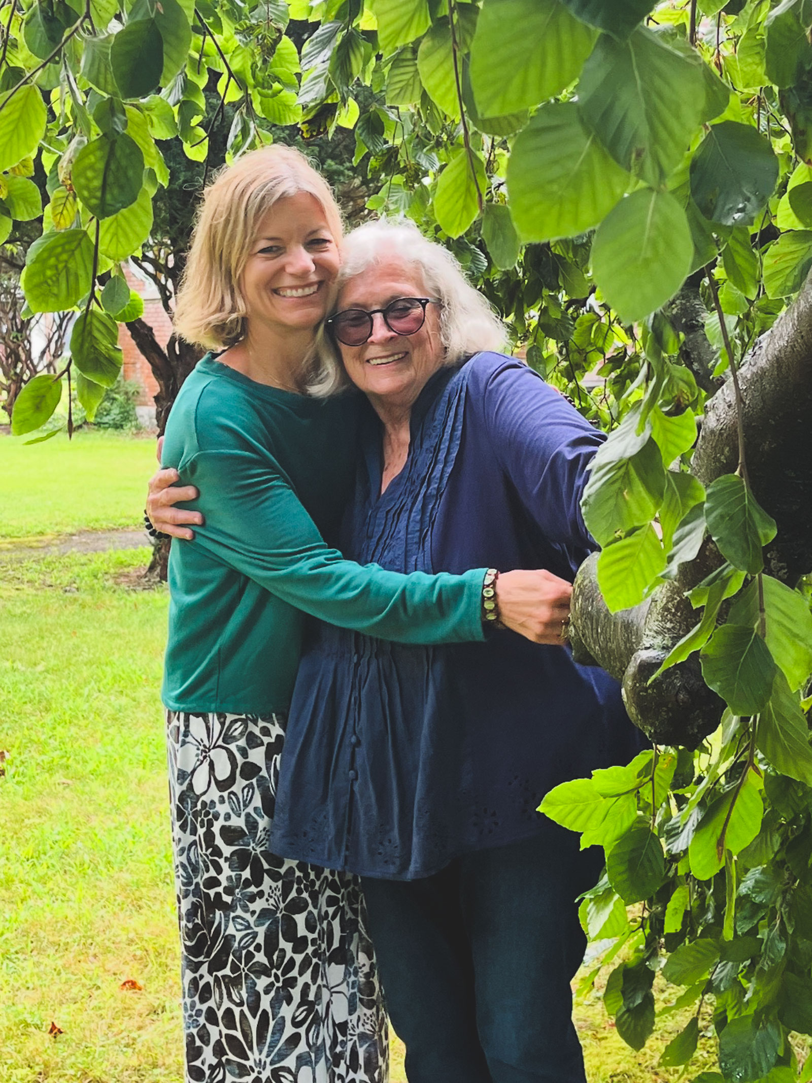 Two people standing near green bush.
